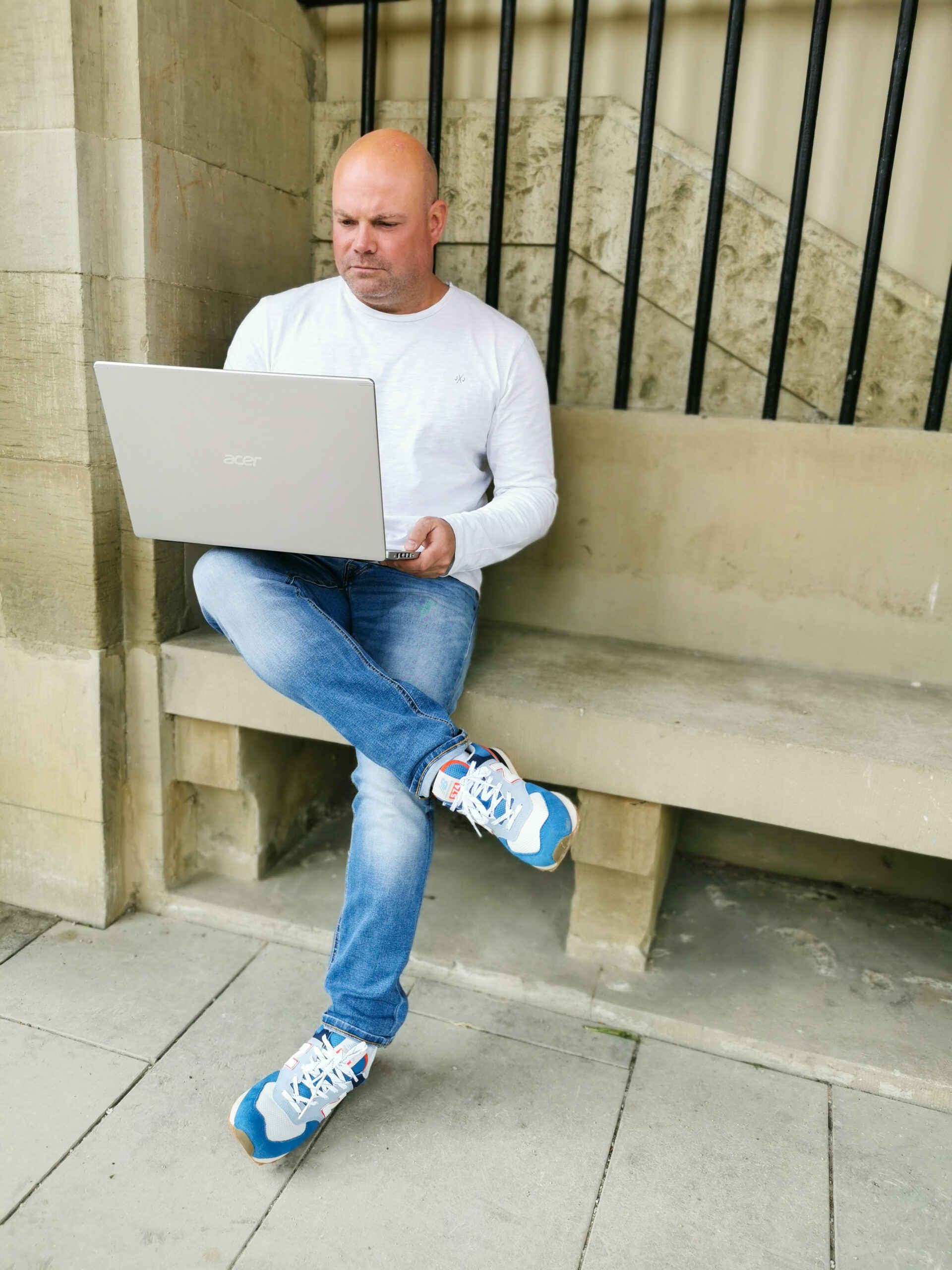 marius metz virtuelle assistenz sitzt draußen auf bank am laptop